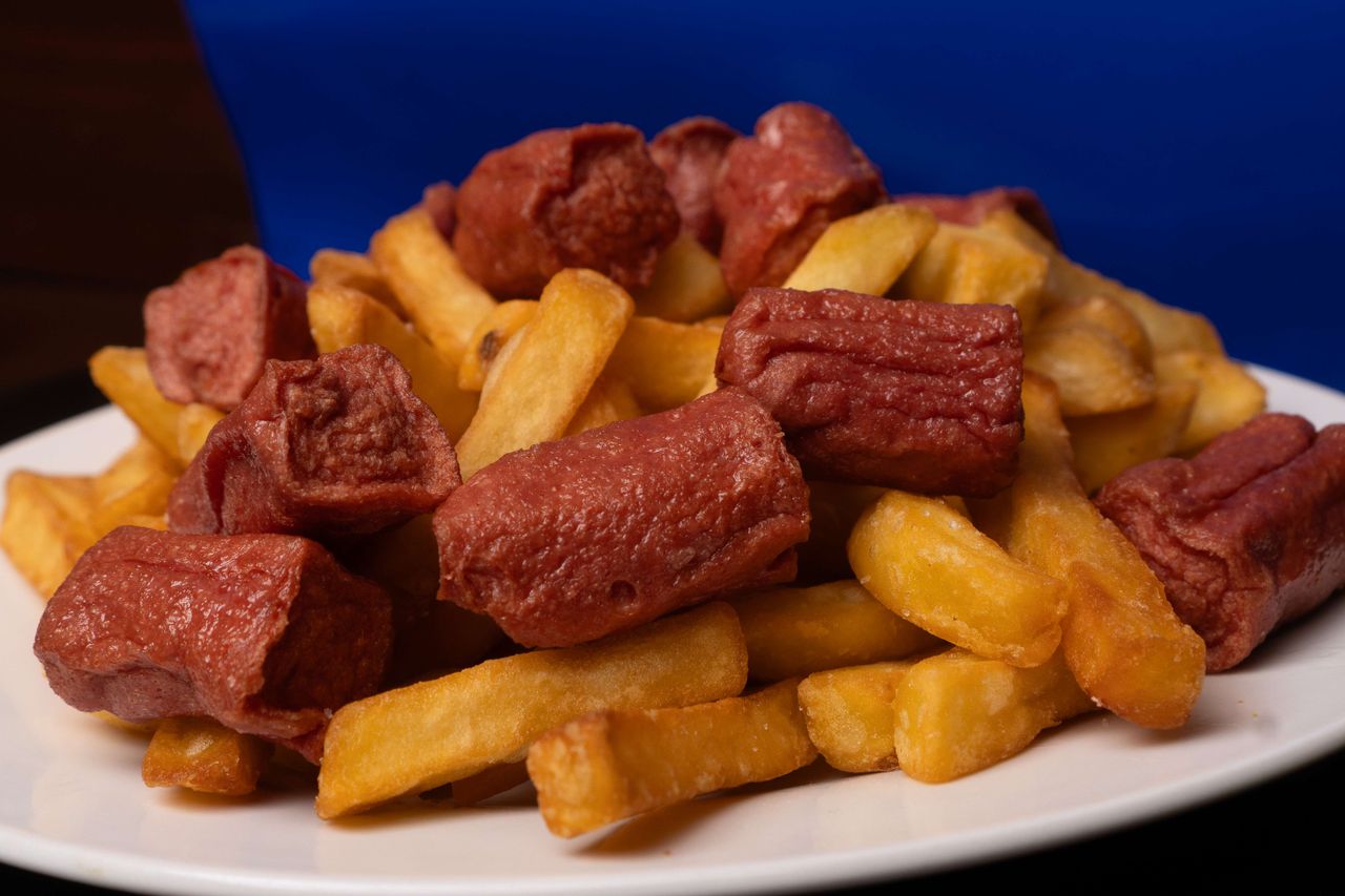 Services Delicious crispy fries paired with savory red sausages served on a white plate.