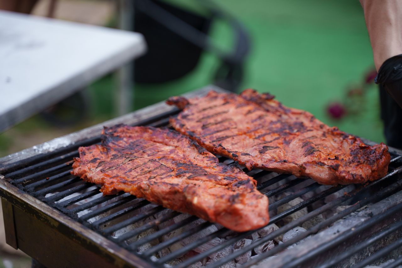 Services Juicy grilled steaks sizzling on an outdoor charcoal barbecue with vibrant summer vibes.